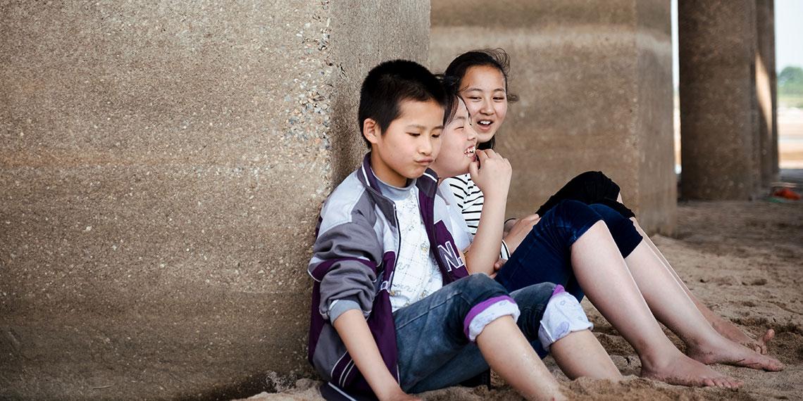 kids sitting against a concrete pillar