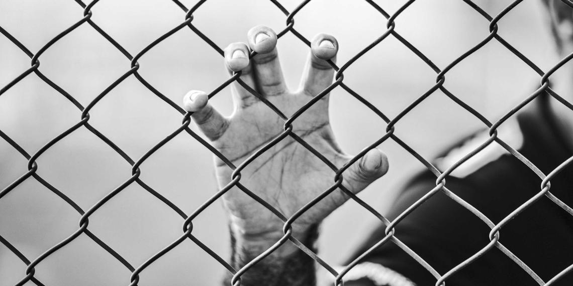 man holding a chain-link fence
