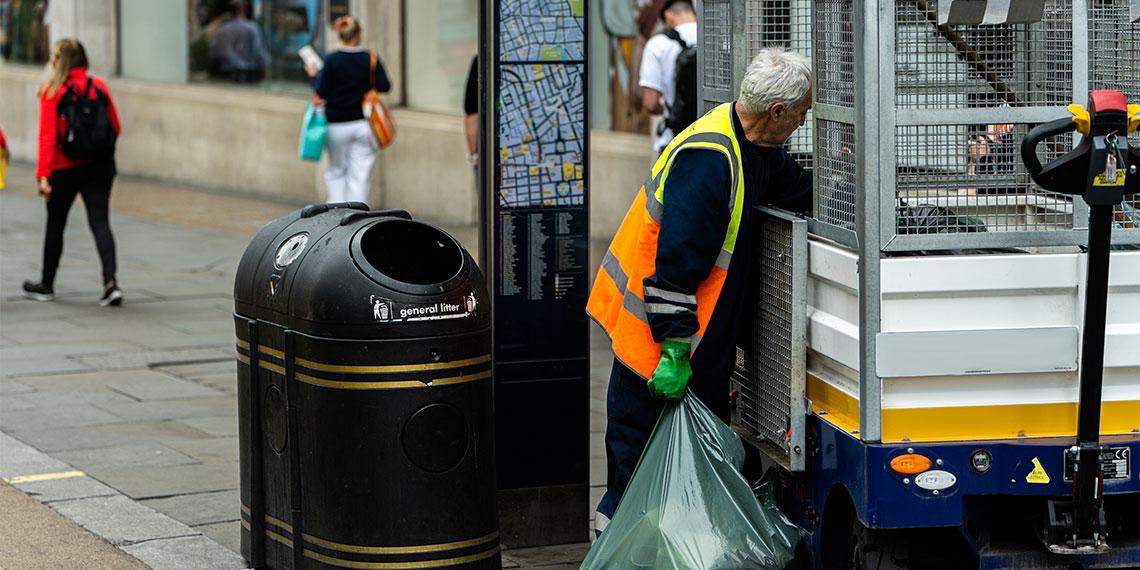 Man in high vis vest collecting rubbish in the city