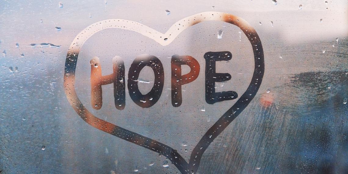 A rainy window with the word Hope written inside a heart shape