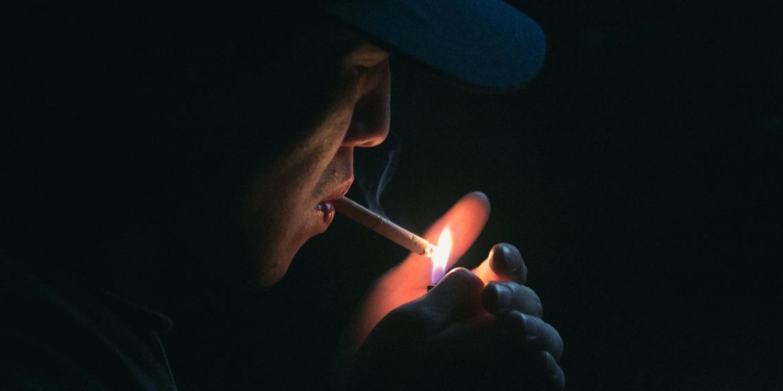 Person in the shadows lighting a cigarette