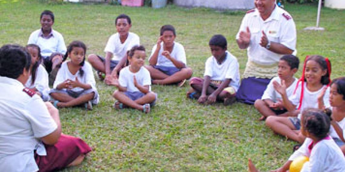 Children singing while sitting on the grass
