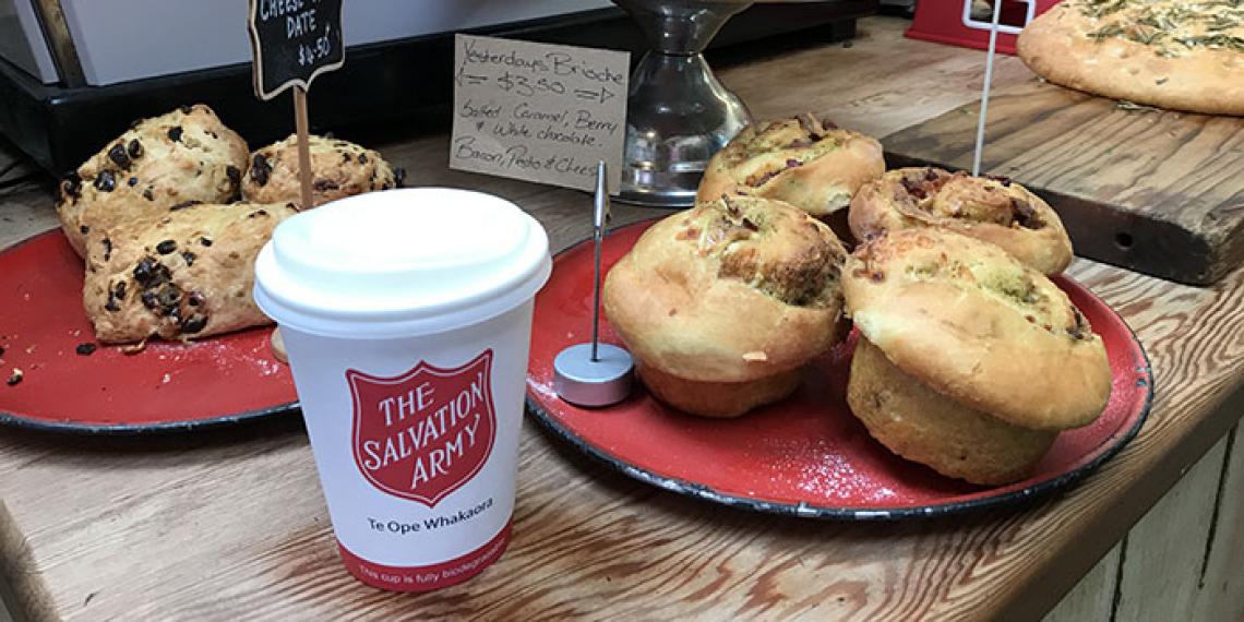 A cup with 'The Salvation Army' wording on it amongst cafe food items