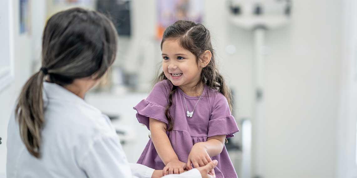 A doctor chatting with a smiling girl in a medical facility