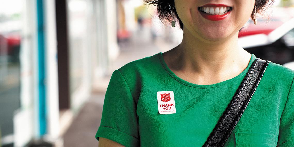 Lady smiling with a Thank You sticker on her shirt