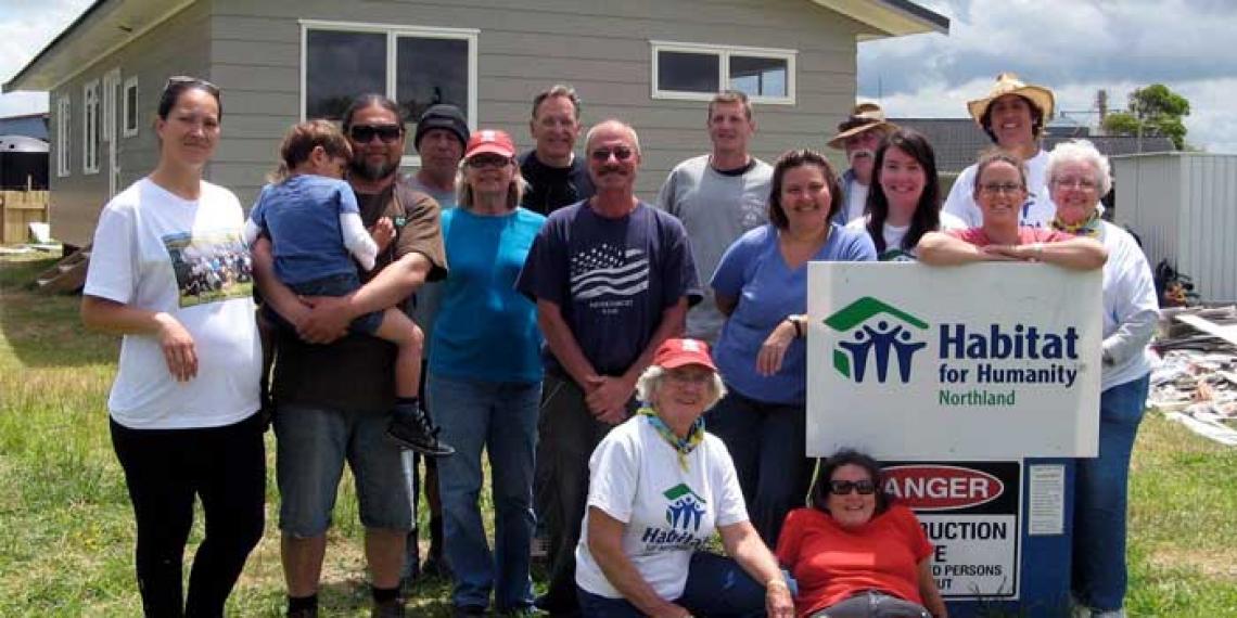 People grouped around a habitat for humanity house 