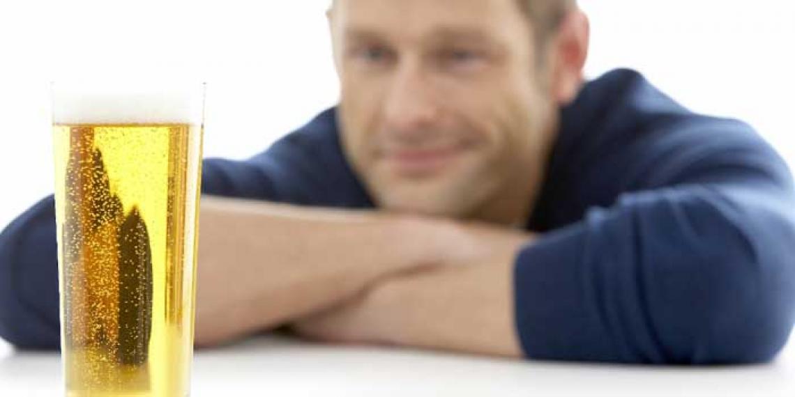 Man looks at a full glass of beer