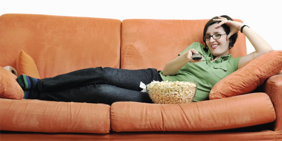 a woman lying on the couch watching movies