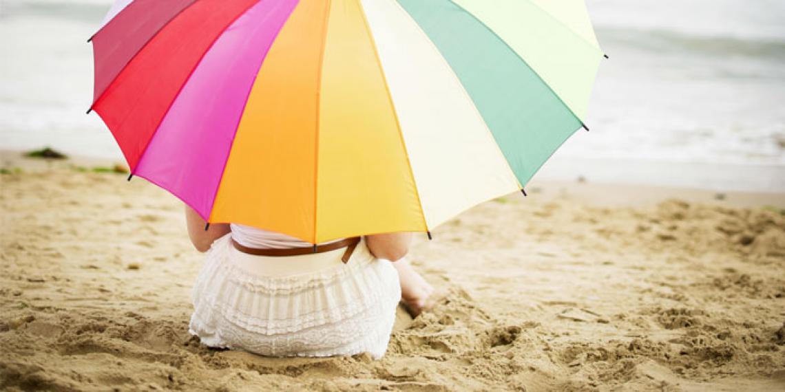 a woman under an umbrella on the beach