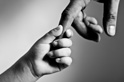A small child reaches up to hold an adult's hand